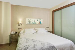 1 dormitorio con 1 cama blanca grande y teléfono en Apartamentos Turísticos Centro, en Granada