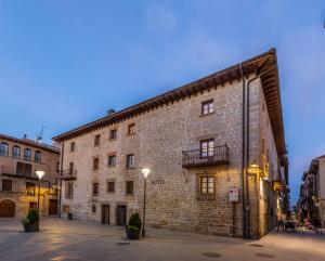 - un grand bâtiment en briques avec un balcon dans une rue dans l'établissement Palacio de Pujadas by MIJ, à Viana
