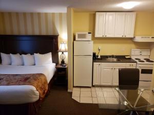 a hotel room with a bed and a kitchen at Arbutus Inn in Victoria