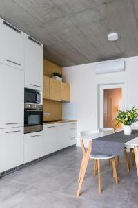 uma cozinha com armários brancos e uma mesa e cadeiras em Residence Trafick em Praga