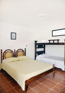 two beds in a room with white walls at Hostal Dumbira in Taganga