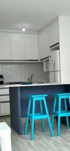 a kitchen with two blue stools in front of a counter at Apartamento com vista para o mar in Jacumã