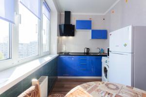a kitchen with blue cabinets and a white refrigerator at Квартира біля ТРЦ "DREAM TOWN 2" in Kyiv