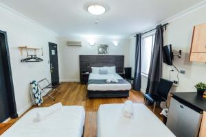 a bedroom with a bed and a desk and a tv at UNO Hotel Sydney in Sydney