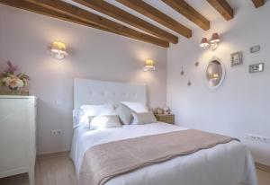 a white bedroom with a large bed with white sheets at La Casa del Tránsito in Toledo