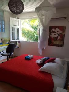Schlafzimmer mit einem großen roten Bett und einem Fenster in der Unterkunft Villa Emmanuel le Plaisir des Vacances in Sainte-Luce