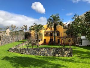 a yellow house with palm trees and a stone wall at The Place in Ponta Delgada