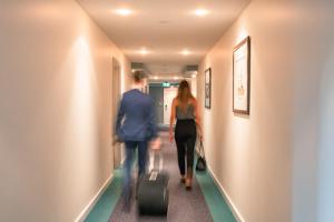 Port Lincoln Hotel في بورت لينكولن: رجل وامرأة يسيران في الممر مع الأمتعة