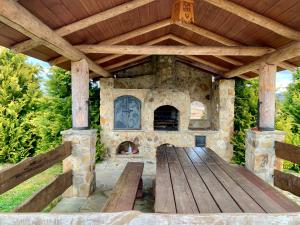 an outdoor patio with a stone fireplace and a wooden table at Domek na górze -Odetchnij od miasta w Istebnej in Istebna
