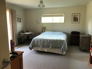 a bedroom with a bed and a table and a window at Fieldays Dream in Tamahere