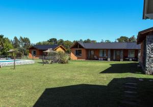 un gran patio con una casa y una piscina en Cabañas Los Sauces en Tandil