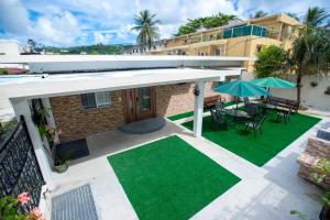 un patio con mesa, sillas y sombrilla en Residence Lodge en Saipan