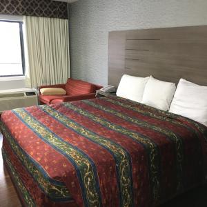 a hotel room with a large bed with a red blanket at Travel Inn & Suites in Humble