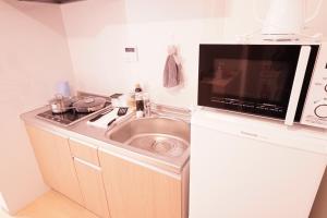 a small kitchen with a sink and a microwave at 暁 Twilight Osaka Inn in Osaka