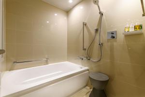 a bathroom with a tub and a shower and a toilet at remm plus Ginza in Tokyo