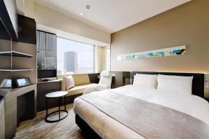 um quarto de hotel com uma cama e um sofá em remm plus Ginza em Tóquio