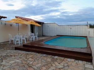 a swimming pool with a table and chairs and an umbrella at Recanto no Caribe in Arraial do Cabo