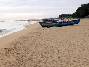 um barco azul sentado numa praia junto ao oceano em DERO BEACH HOLIDAY HOME em Batticaloa