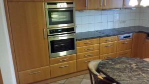 a kitchen with wooden cabinets and stainless steel ovens at Ferienhaus Schwörer in Rheinhausen