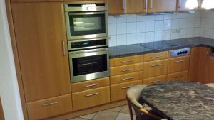 eine Küche mit Holzschränken und Öfen aus rostfreiem Stahl in der Unterkunft Ferienhaus Schwörer in Rheinhausen