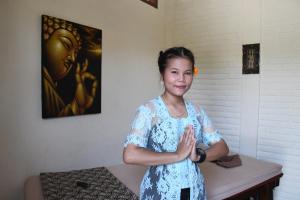 Una donna con un vestito blu in piedi in una stanza di Bruga Villas Restaurant and Spa a Selong Belanak