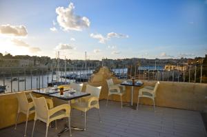 a patio with tables and chairs on a balcony at Villa Del Porto in Kalkara