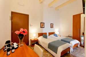 a hotel room with two beds and a table with flowers at Villa Del Porto in Kalkara