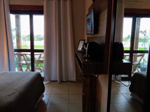 1 dormitorio con cama, TV y balcón en Pousada Águas do Mampituba, en Torres