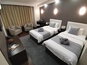 um quarto de hotel com duas camas e uma mesa e cadeiras em Corona Hotel em Vladivostok