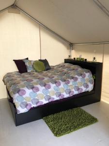a bed in a room with a green rug at Vines and Puppies Glamping Hideaway in Jade City