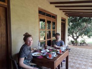 un hombre y una mujer sentados en una mesa comiendo comida en Shan Mango Homestay, en Sigiriya