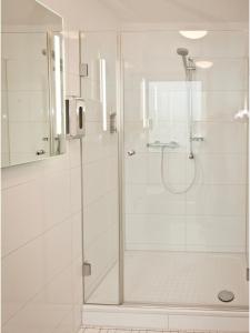 Baño blanco con ducha con puerta de cristal en Hotel Edel Weiss, en Bremen