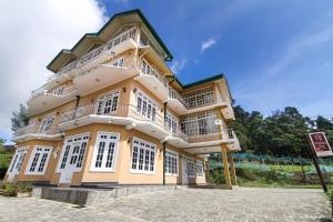 - un grand bâtiment jaune avec un balcon en haut dans l'établissement Thilina Hotel, à Nuwara Eliya