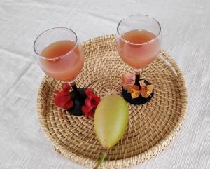 twee glazen thee en een peer op een rieten bord bij TI CALEBASSE in Le Vauclin