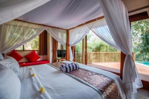 The Grand Bakas Jungle Retreat Villa في Klungkung: غرفة نوم مع سرير مظلة وسطح
