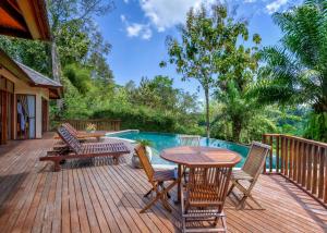 KlungkungにあるThe Grand Bakas Jungle Retreat Villaのプールサイドのデッキ(テーブル、椅子付)