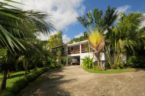 une maison avec des palmiers devant elle dans l'établissement Villa de la Vallée, à Rodrigues Island
