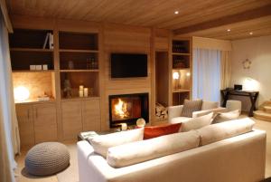 a living room with a white couch and a fireplace at Le Grand Chalet et Spa in Niedermorschwihr
