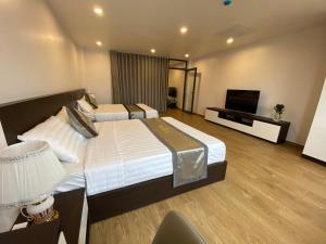 a hotel room with two beds and a flat screen tv at Novatel Hotel & Apartment in Hai Phong