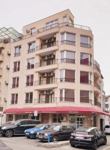 a tall building with cars parked in front of it at Family Aparthotel Vintegra in Burgas