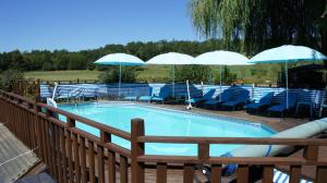 a swimming pool with blue chairs and umbrellas at Les Tachats in Hautefort