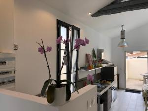 - une cuisine avec un vase orné de fleurs violettes dans l'établissement Le clos du square, à Rochefort