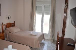 a bedroom with two beds and a window at Hotel Doña Carmen in Ronda