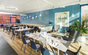 ein Restaurant mit Tischen und Stühlen und einer blauen Wand in der Unterkunft Hotel INNdependence in Mainz