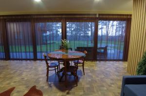 a dining room with a table and chairs and windows at Žvėrinčiaus vila in Birštonas