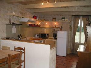 een keuken met een witte koelkast en een tafel bij The Cottage in Hautefort