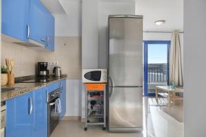 La cuisine est équipée de placards bleus et d'un réfrigérateur en acier inoxydable. dans l'établissement El Rincón de Famara, à Famara