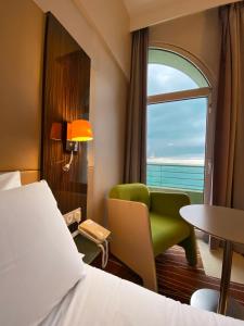 a hotel room with a bed and a chair and a window at Mercure Granville Le Grand Large in Granville