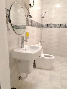 a bathroom with a sink and a toilet and a mirror at Turtle Guest House in Sur