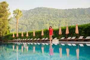 a woman standing next to a swimming pool with umbrellas at Akka Claros Hotel - All Inclusive in Kemer
